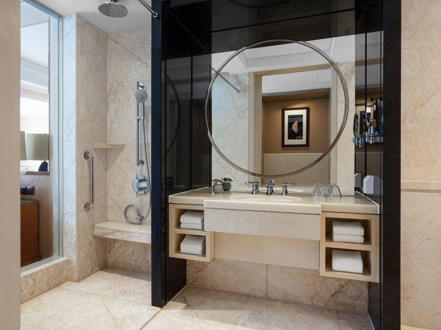 A modern bathroom with a large mirror, a shower, and a vanity with towel racks.