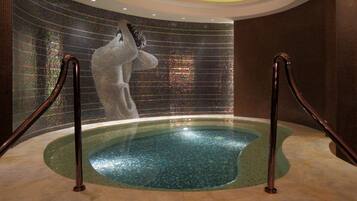 A hot tub with mosaic walls and metal railings.