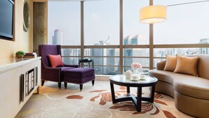 A modern hotel room with a large city view, a purple armchair, a beige sofa, and a round coffee table. - Guangzhou Marriott Hotel Tianhe (Guangzhou)