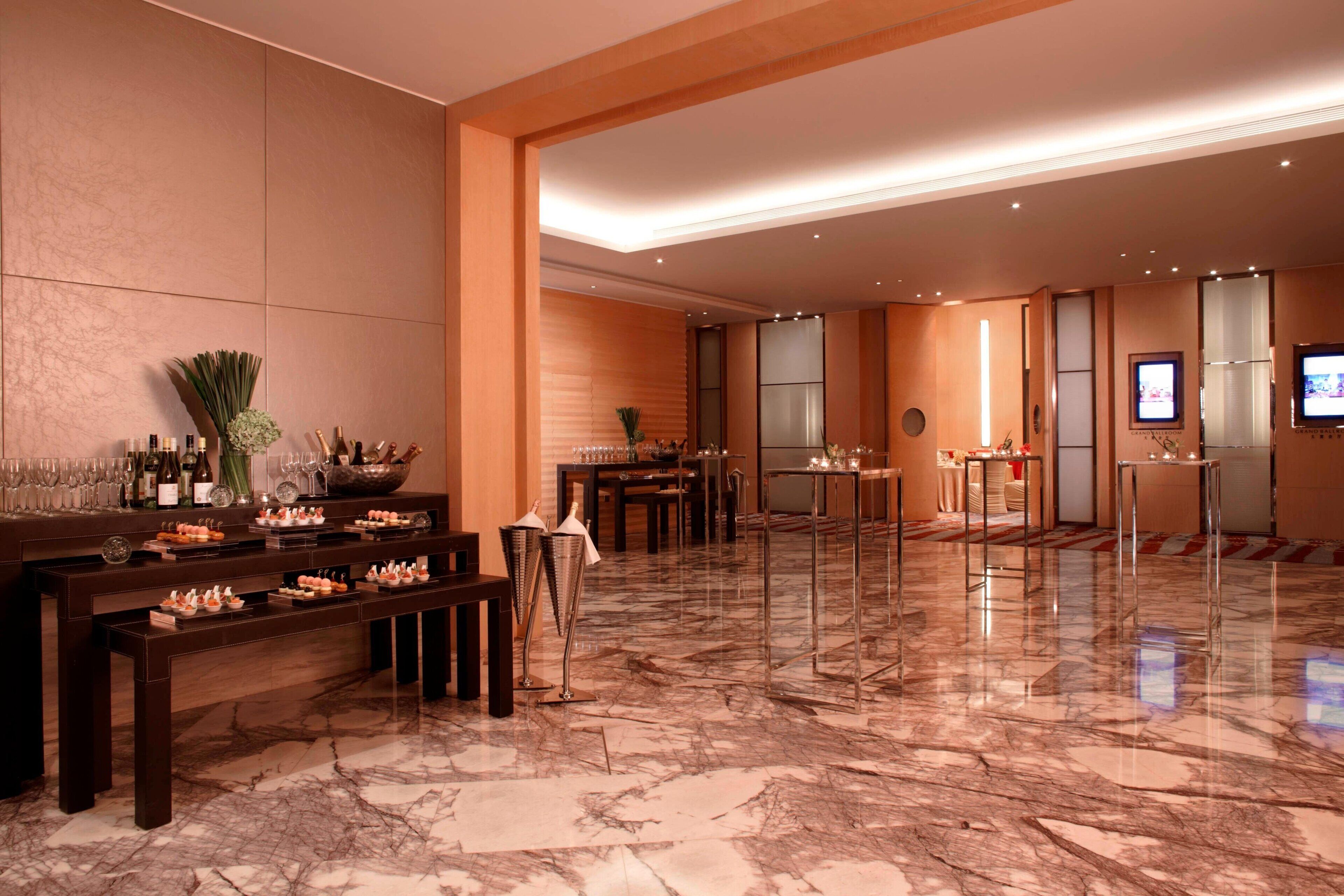 A spacious lobby with a marble floor, a reception desk, and a seating area with tables and chairs.