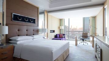 A modern hotel room with a large bed, a desk, and a view of the city.