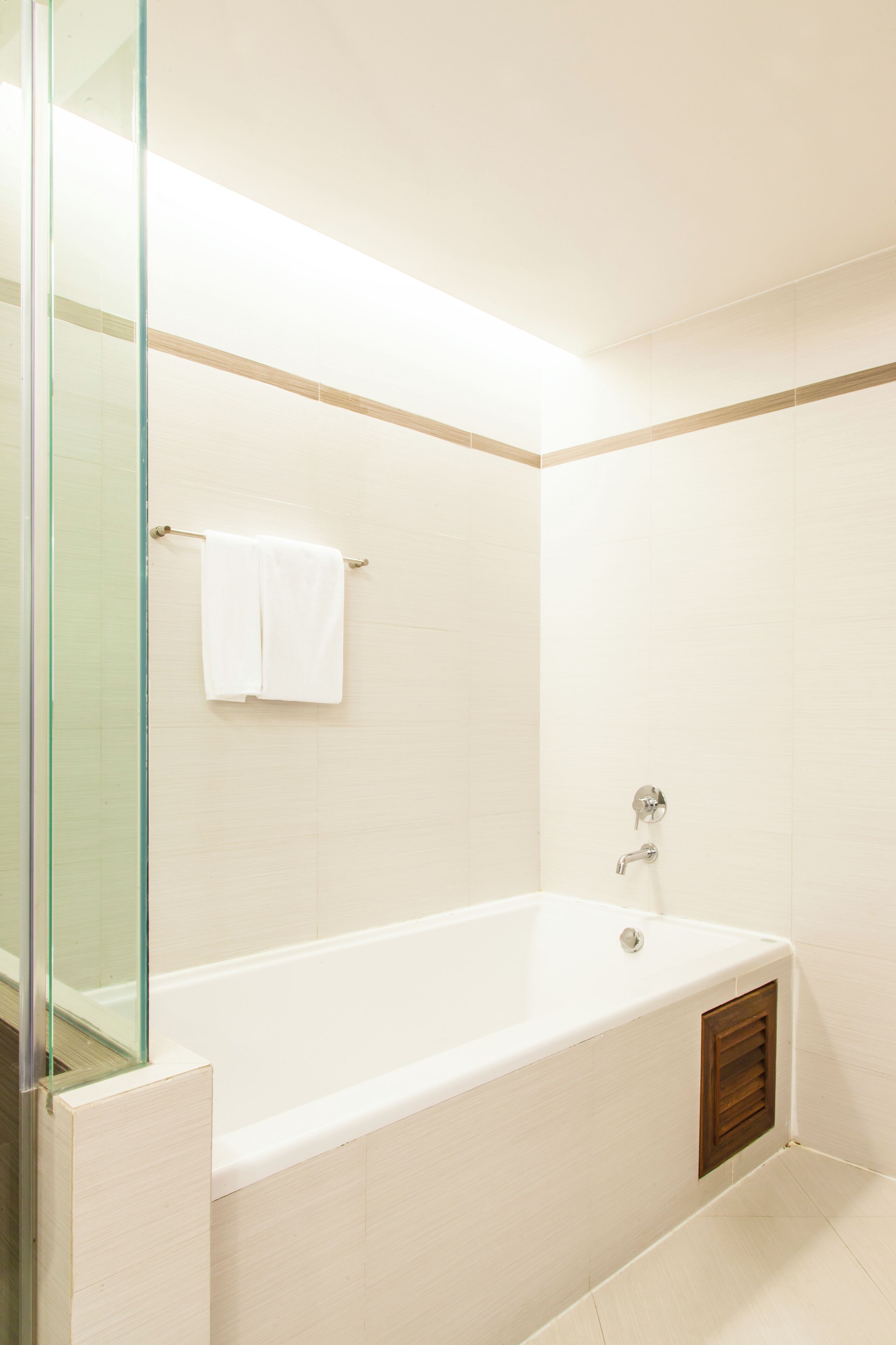 Un baño moderno con bañera, cabina de ducha de cristal y un perchero para toallas.