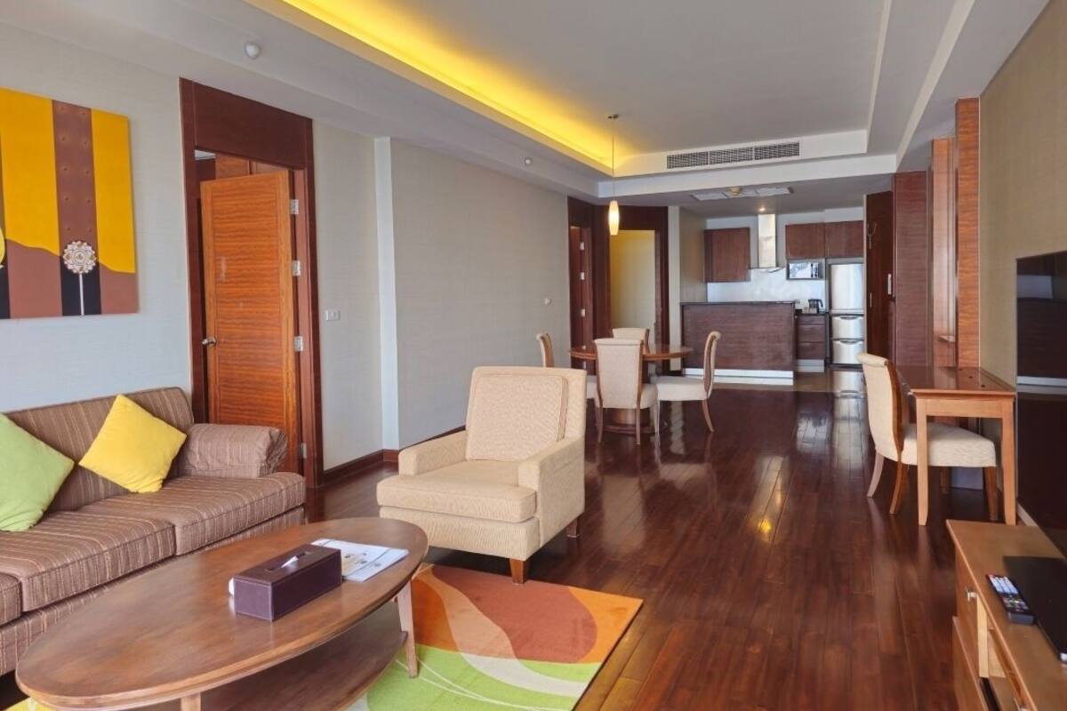 Una habitación de hotel moderna con una sala de estar, un comedor y una cocina al fondo.