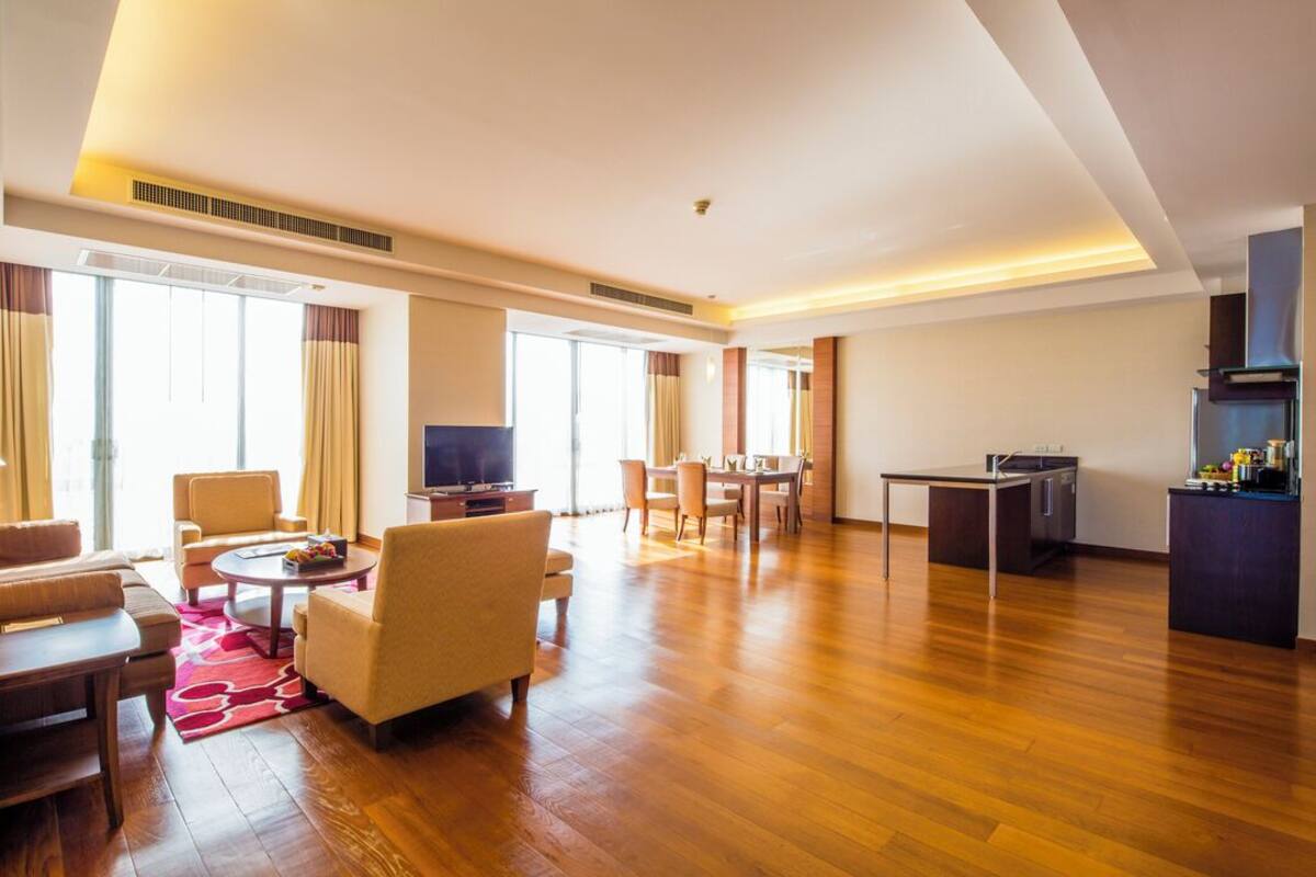 Amplia sala de estar con piso de madera, una mesa de comedor y una cocina con pileta y estufa.