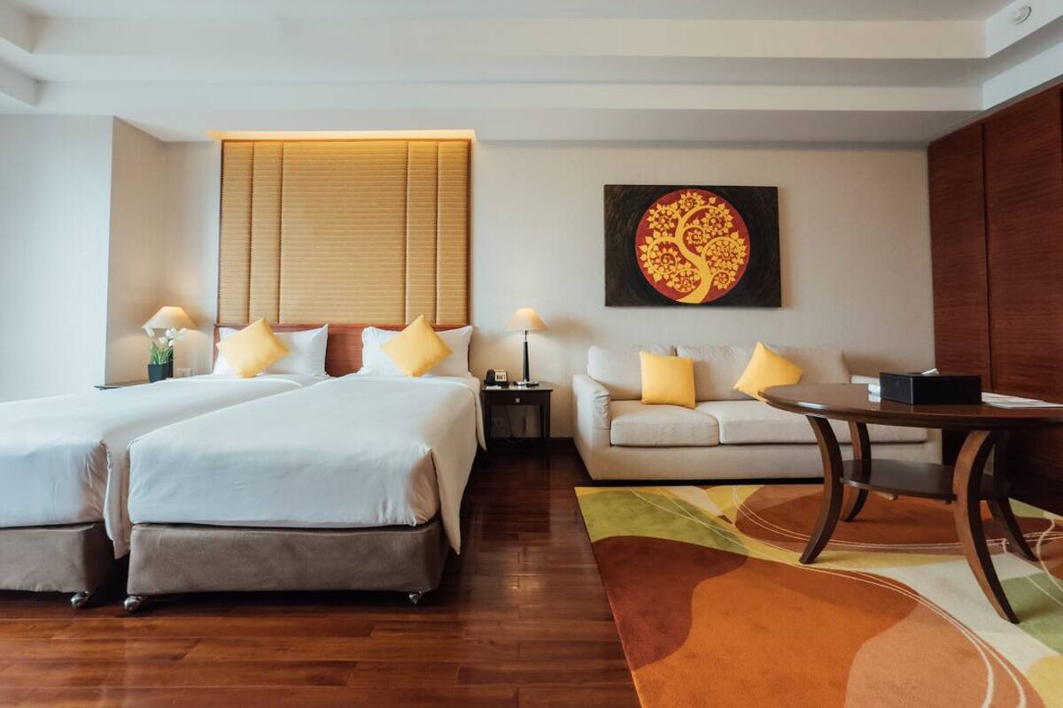 Habitación de hotel con dos camas, un sofá, una mesa de comedor y una pared decorada.
