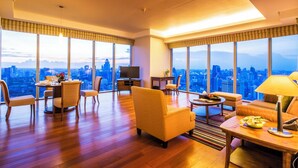 A spacious living room with a city view, a dining area, and a seating area with a table and chairs.