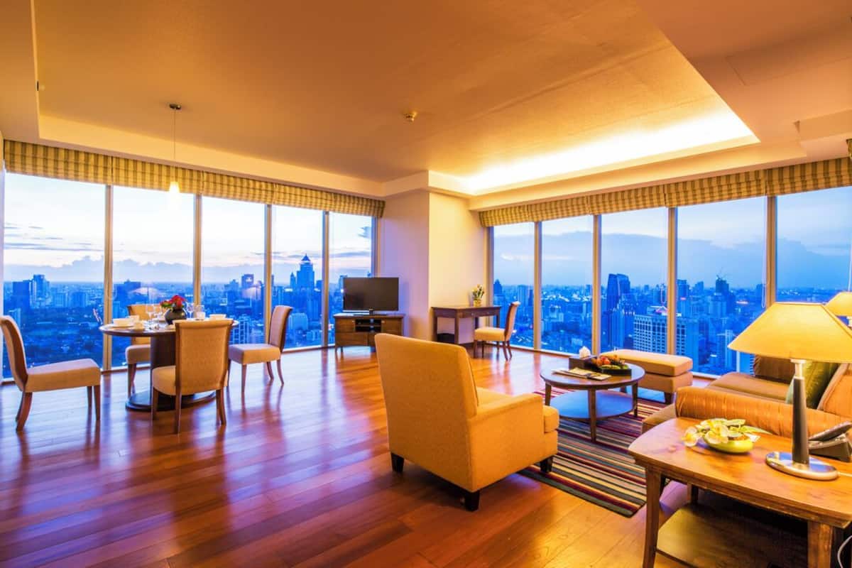Amplia sala de estar con vistas a la ciudad, un comedor y un espacio de descanso con mesa y sillas.
