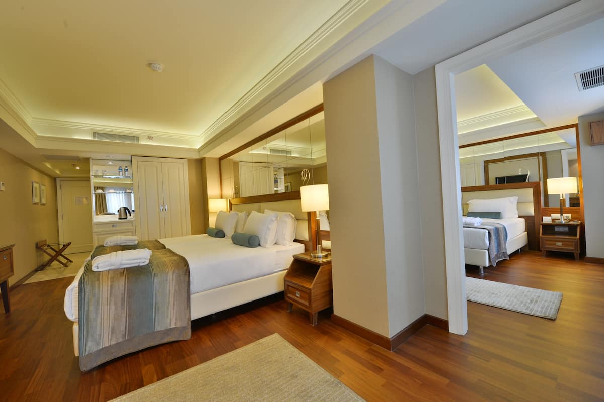 Een hotelkamer met een groot bed, nachtkastjes, een spiegel en een zichtbare badkamer door een geopende deur.