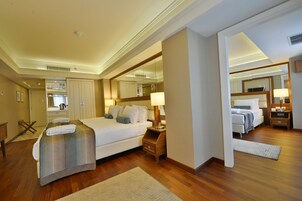Habitación de hotel con una cama grande, mesitas de noche, un espejo y un baño visible a través de una puerta abierta.