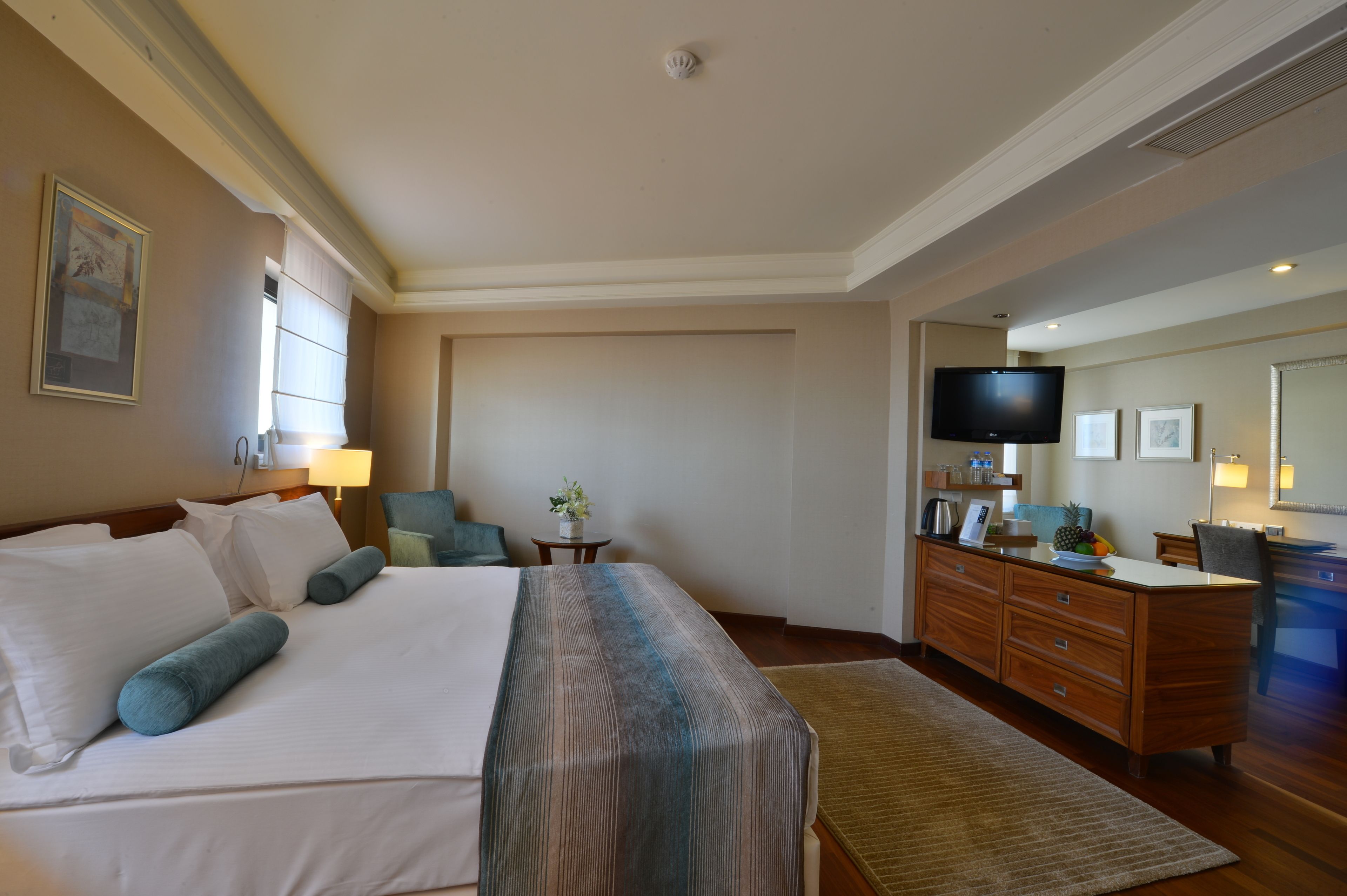 A hotel room with a large bed, a desk, a television, and a window.