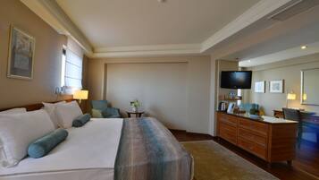 A hotel room with a large bed, a desk, a television, and a window.
