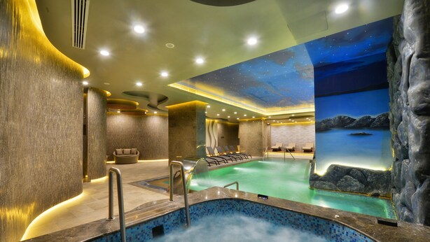 Área de spa com hidromassagem, cadeiras de descanso e um mural representando um céu noturno.