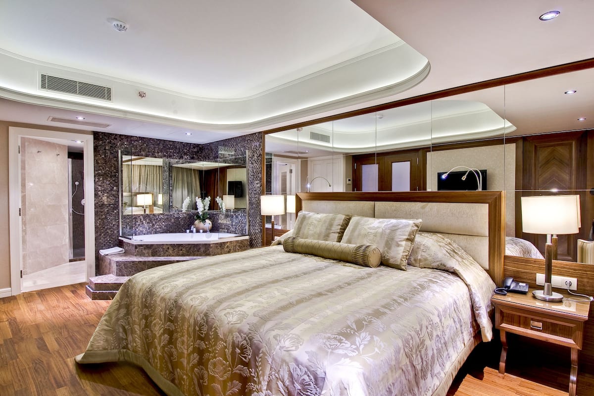 Een hotelkamer met een groot bed, een badkamer met een marmeren wand en een televisie aan de muur.
