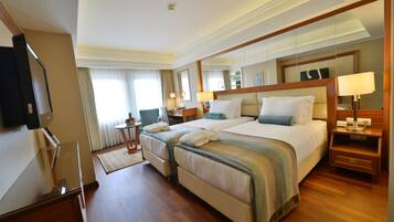 A hotel room with two beds, a TV, a desk, and a mirror.