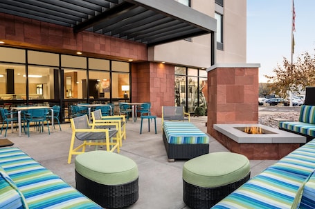 An outdoor patio area with seating, a fire pit, and a bar with chairs and tables.
