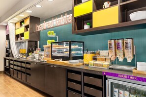 Un buffet de petit-déjeuner en libre-service proposant une variété d’aliments, notamment des yaourts et du lait, ainsi qu’un panneau indiquant : « Table d’inspiration ».