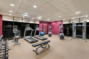 Un gimnasio moderno con cintas de correr, máquinas de pesas y una banca.