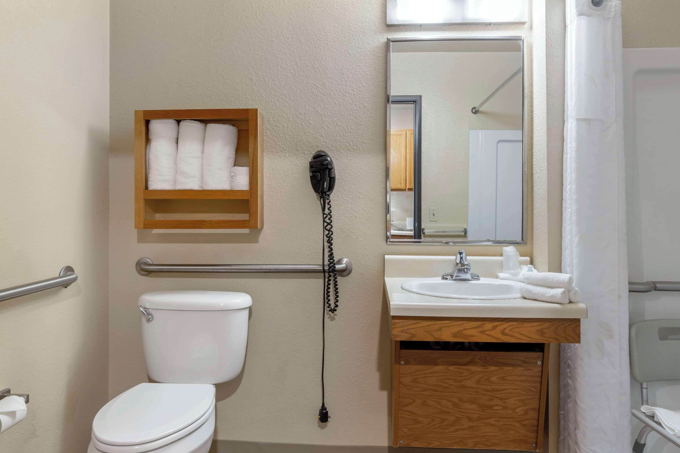 A bathroom with a toilet, a sink, a mirror, and a towel rack.