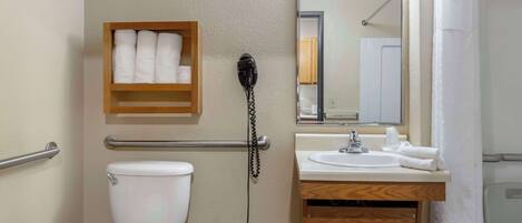 A bathroom with a toilet, a sink, a mirror, and a towel rack.