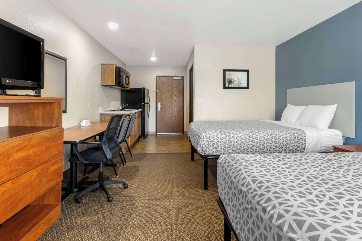 Ein Hotelzimmer mit einem Bett, einem Schreibtisch mit Stuhl, einem Fernseher, einer Mikrowelle und einer Tür.