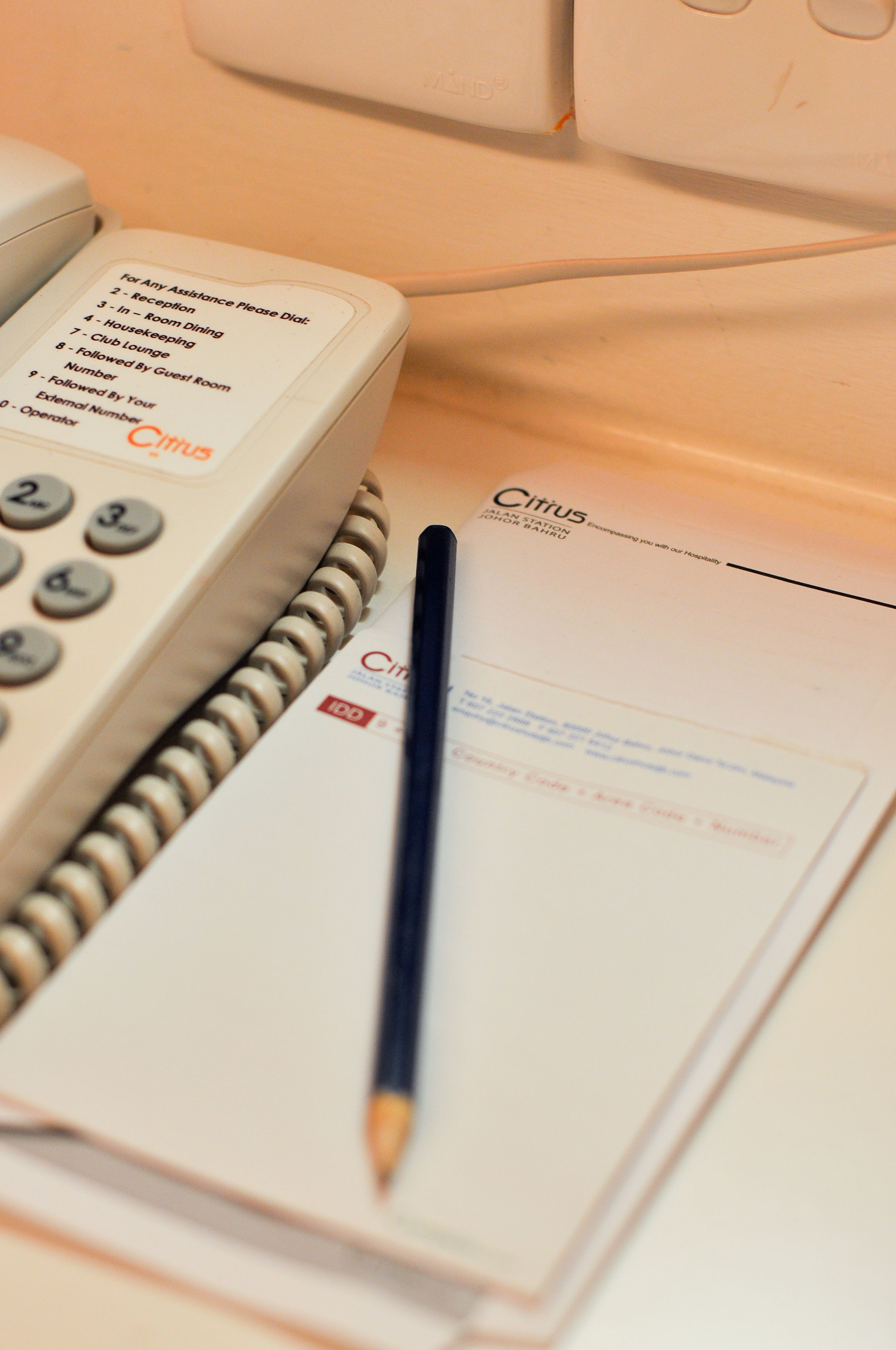 A hotel phone, a notepad, and a pen on a table.