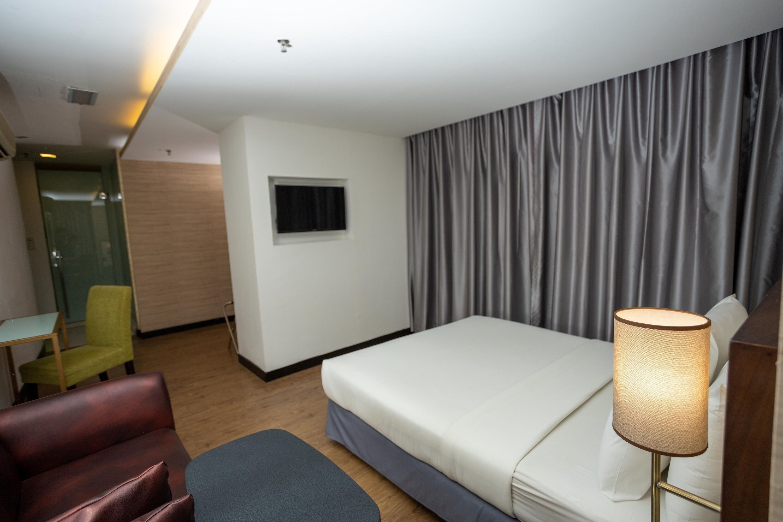 Una habitación de hotel con cama, escritorio, silla, televisión y lámpara.