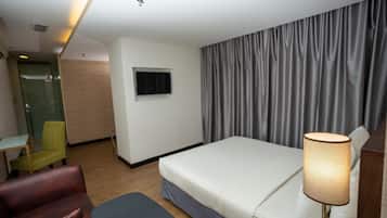 Una habitación de hotel con cama, escritorio, silla, televisión y lámpara.