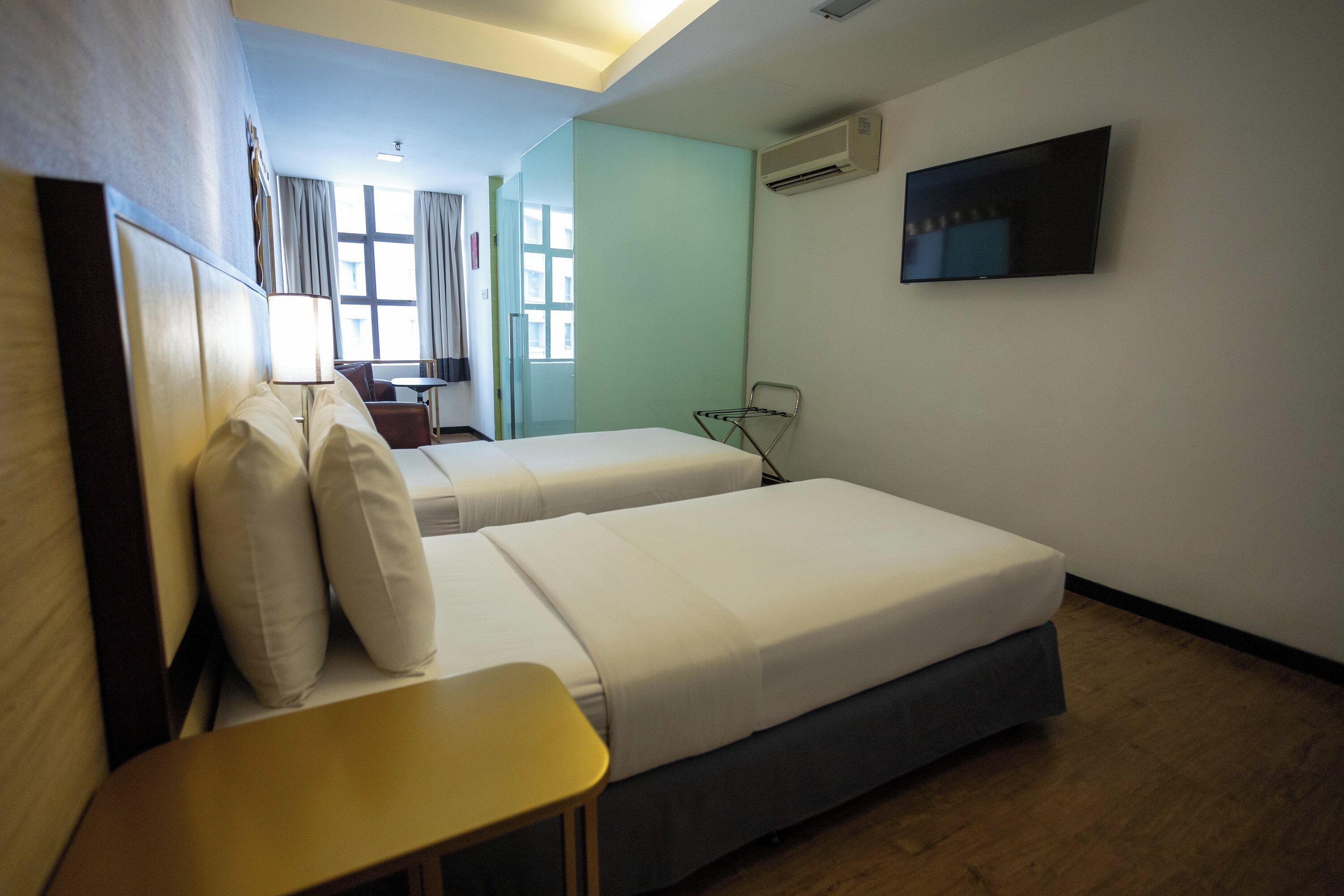 Ein Hotelzimmer mit zwei Betten, einem Fernseher, einem Schreibtisch und einem Fenster.