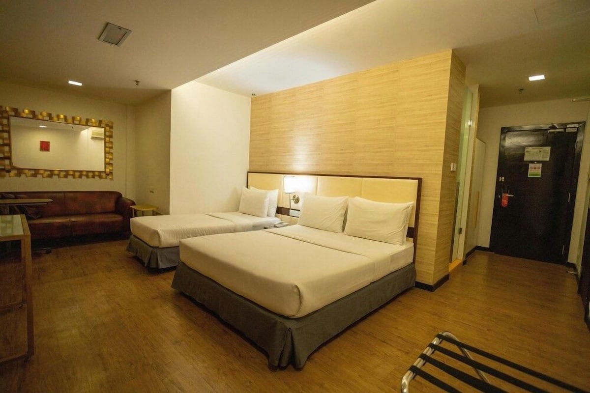 Une chambre d’hôtel avec deux lits, une tête de lit en bois, un miroir, un bureau et une porte.