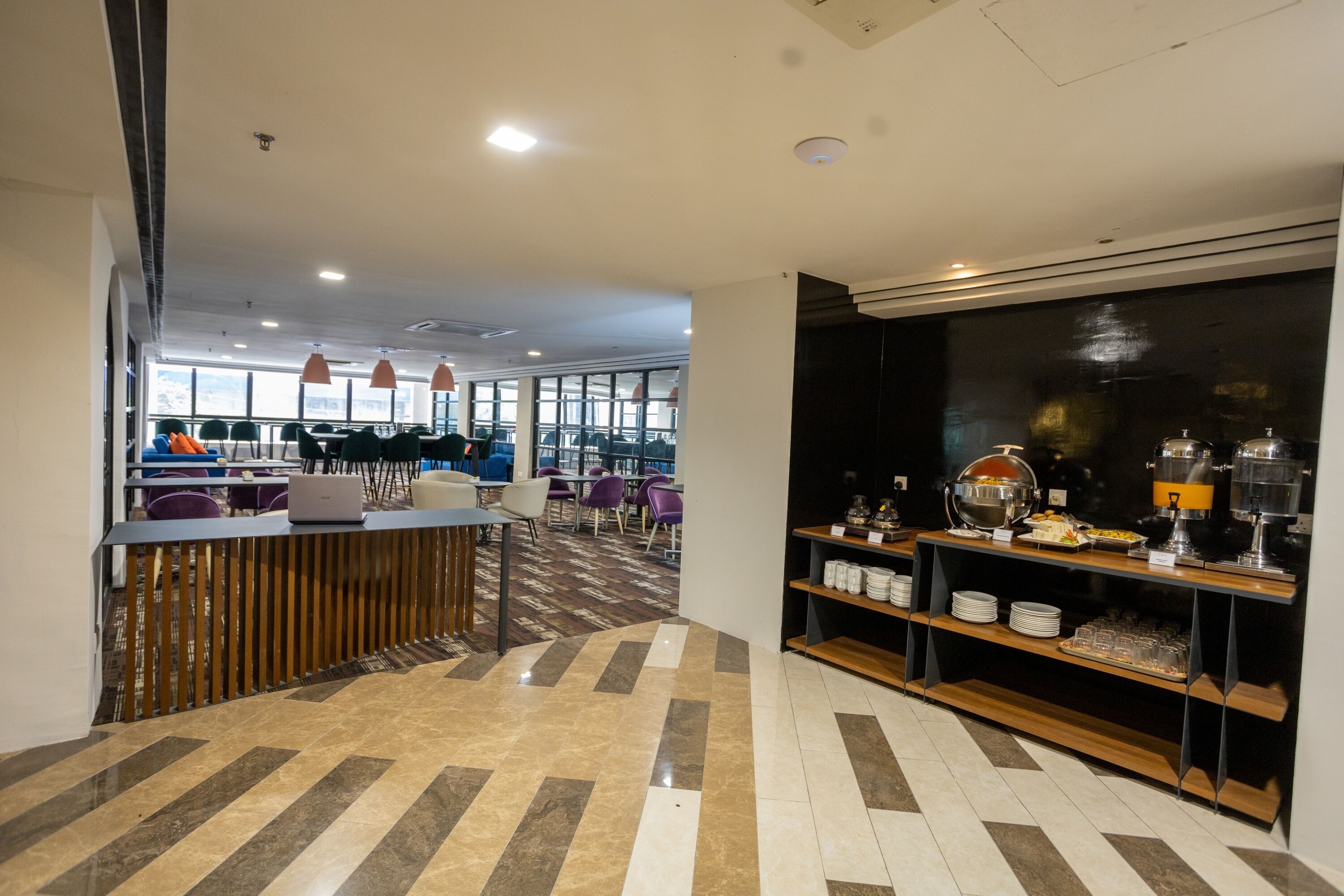 A modern hotel lobby with a reception desk, seating area, and buffet.