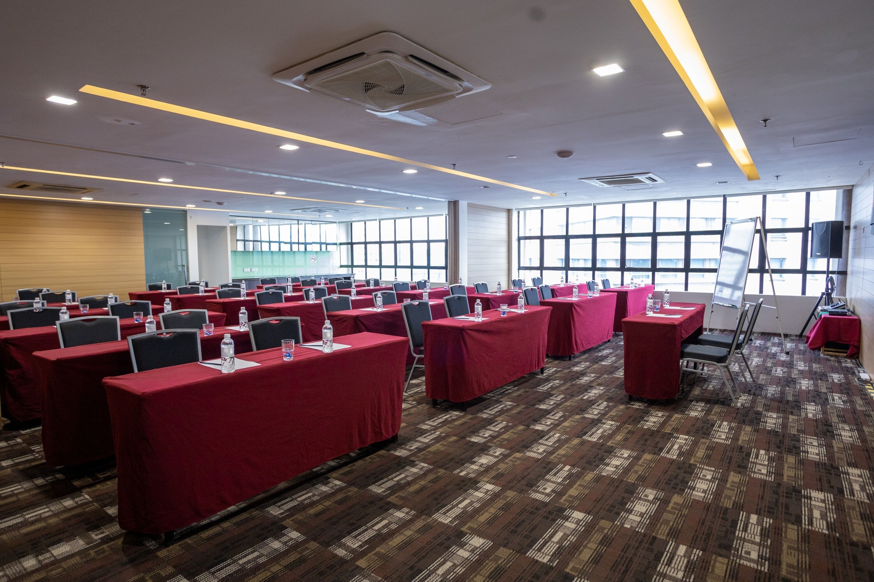 A conference room with rows of tables, chairs, and a projector screen.