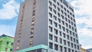 A tall hotel building with a modern design, featuring a grid of windows and a prominent sign at the top.