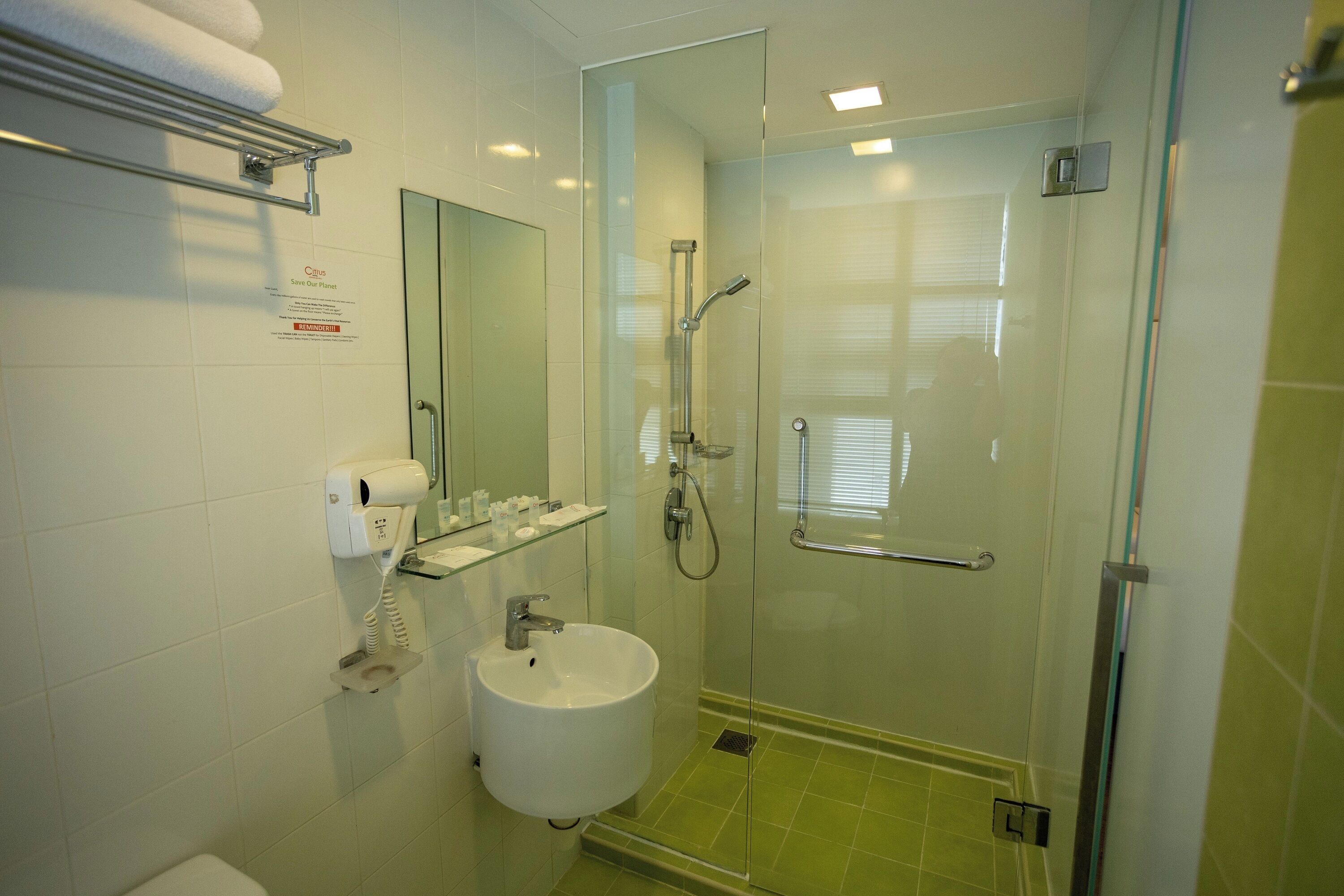 Un baño con cabina de ducha de vidrio, un lavamanos, un perchero para toallas y un espejo.