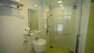 Un bagno con cabina doccia in vetro, lavandino, porta asciugamani e specchio.