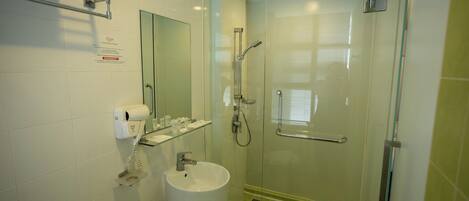 Un baño con cabina de ducha de vidrio, un lavamanos, un perchero para toallas y un espejo.