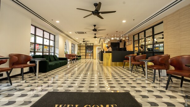 A hotel lobby with a check-in counter, seating area, and a 'WELCOME' mat.