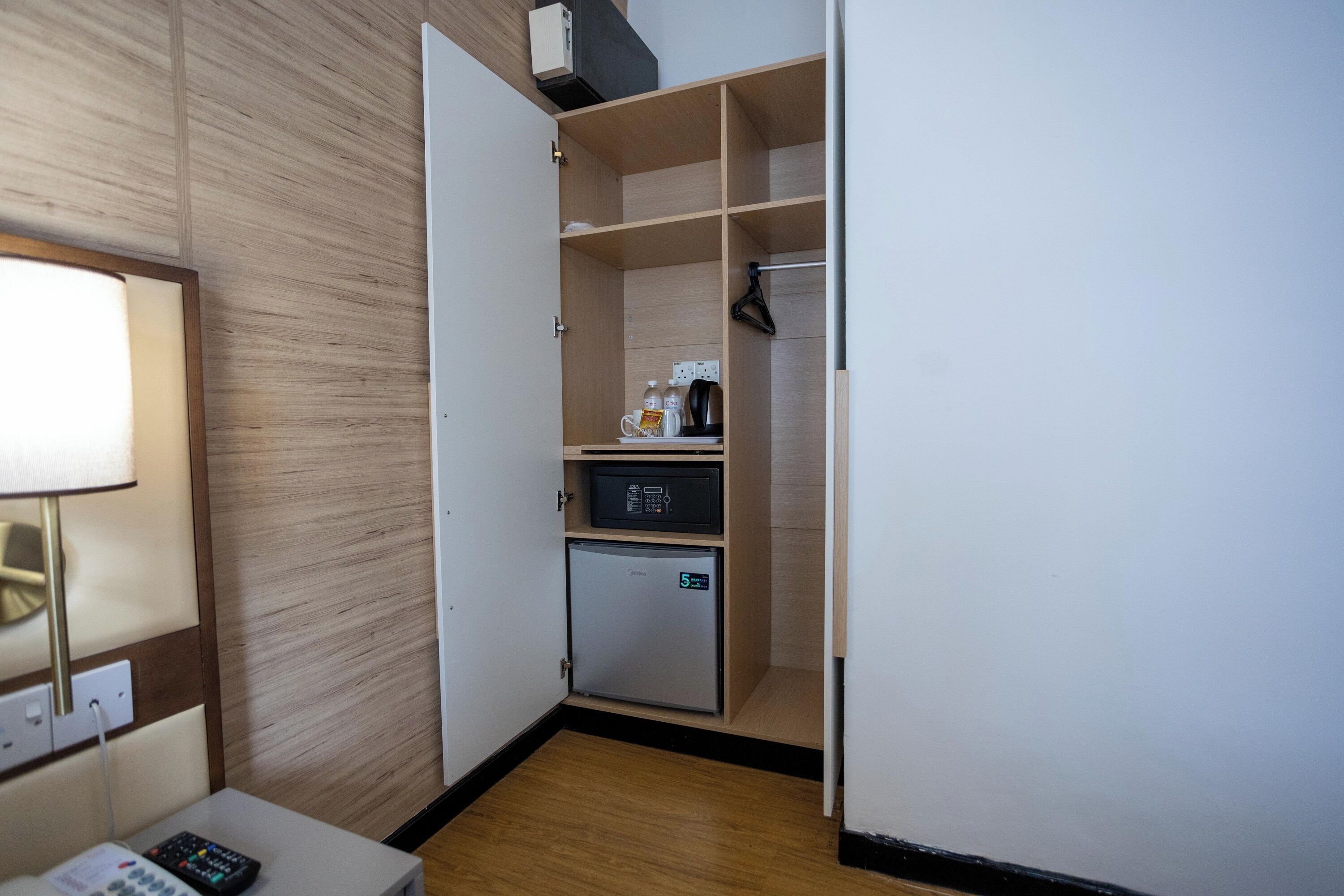 A compact hotel room with a kitchenette, a small refrigerator, a microwave, and a coffee maker on the counter.