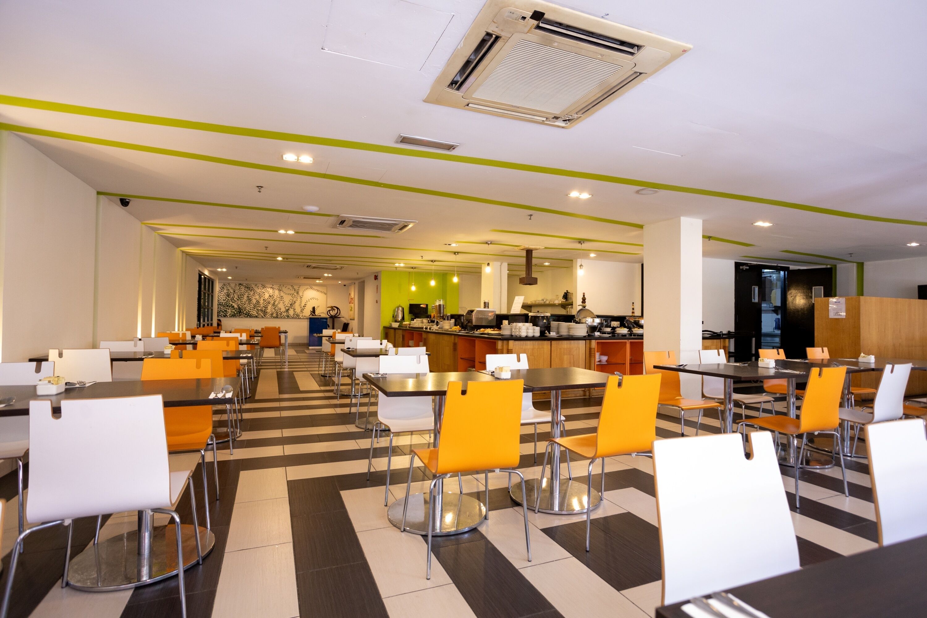 Un comedor moderno con varias mesas y sillas, una cocina al fondo y un suelo con diseño.