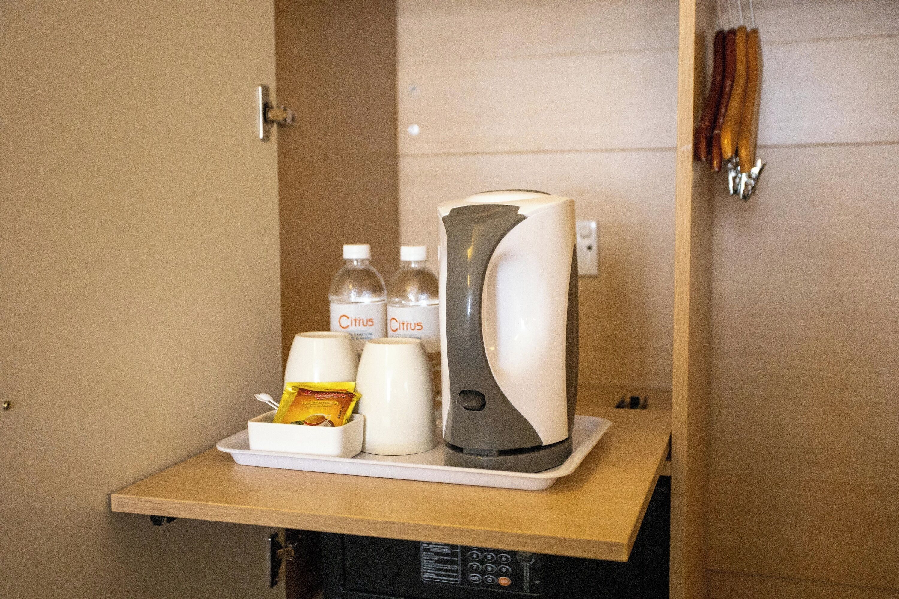 A kitchenette with a coffee maker, two cups labeled 'Citrus,' and a tray with a bag of snacks.