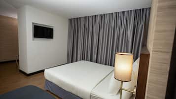 A hotel room with a bed, a bedside lamp, a window, and a curtain.