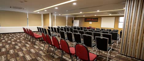 A conference room with rows of chairs, a whiteboard, and a projector screen.