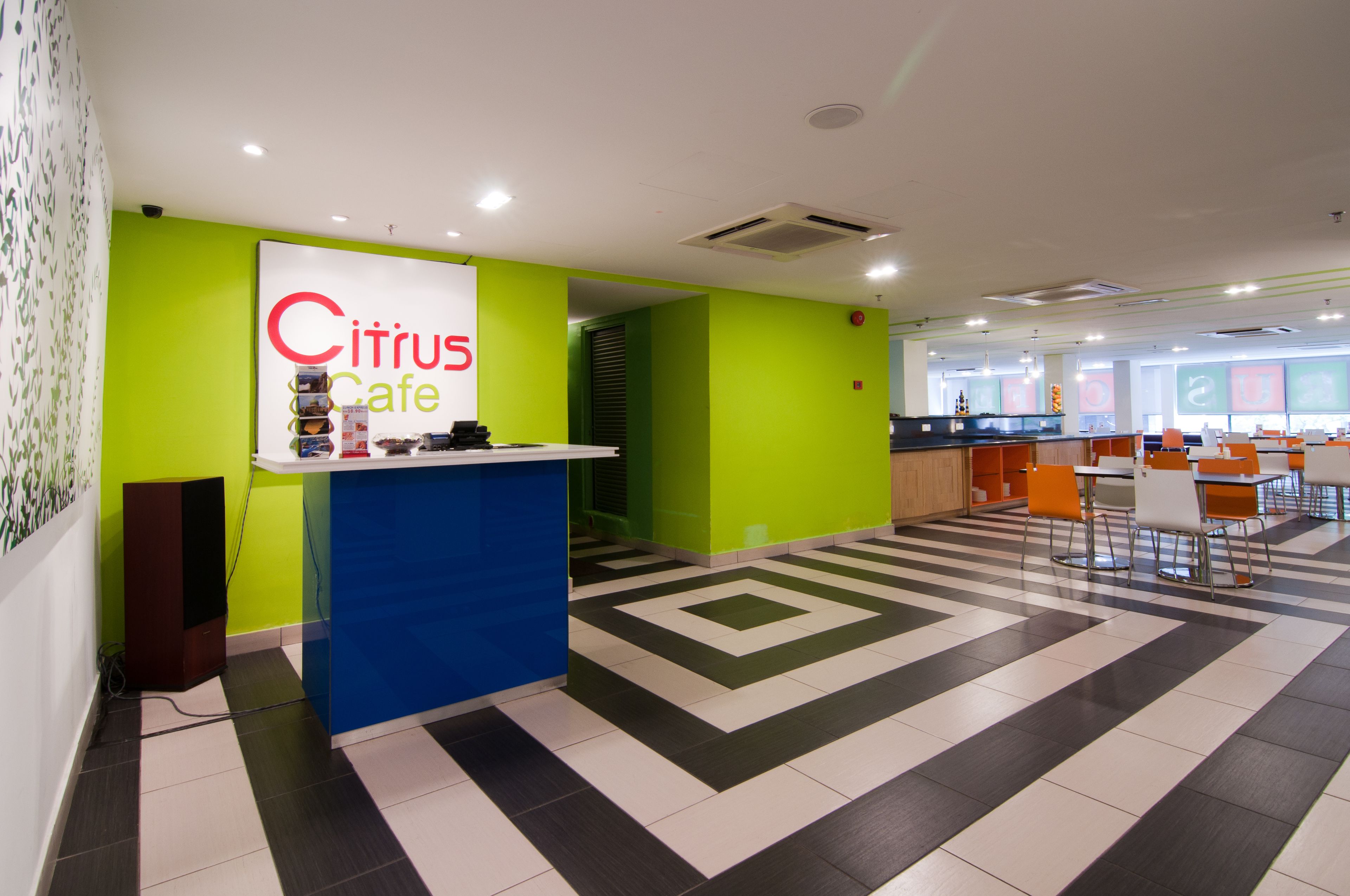 Interior de café moderno com balcão de check-in, área de estar e piso estampado.