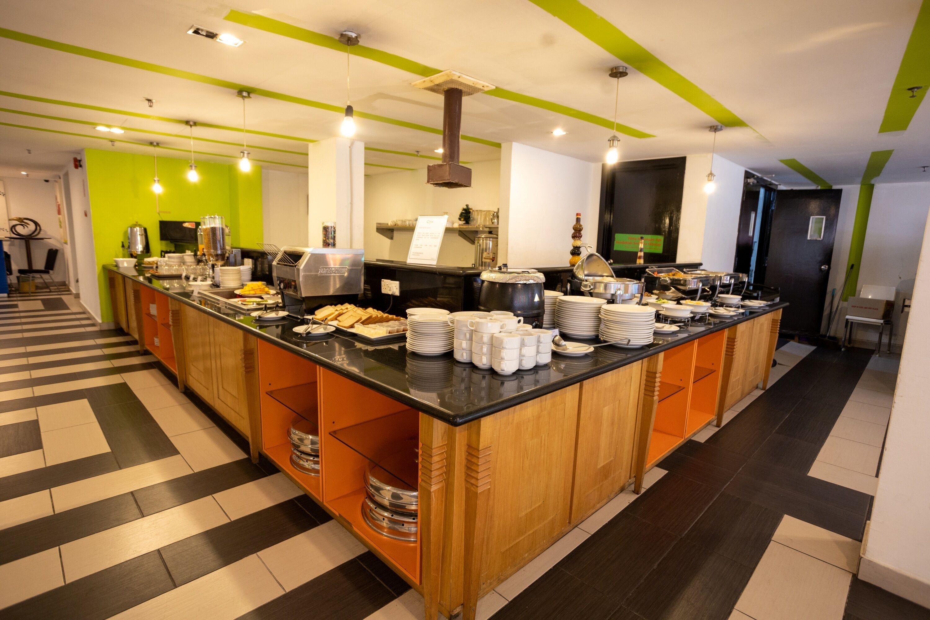 Un área de cocina moderna con una isla central repleta de alimentos y utensilios, rodeada de armarios de madera y una encimera negra.