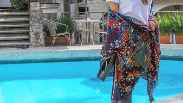 A person standing by a pool with a building in the background.
