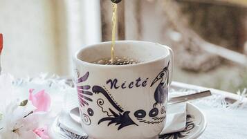 A hand pouring a dark liquid into a cup with a decorative design and the word "Nicté" on it.