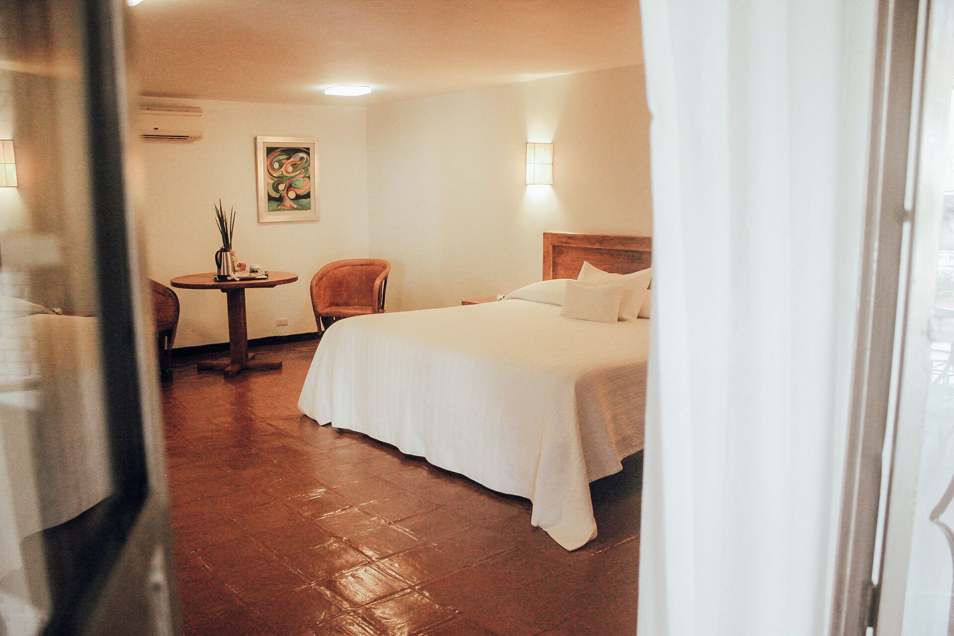 Een hotelkamer met een bed, een stoel, een klein tafeltje en een schilderij aan de muur.