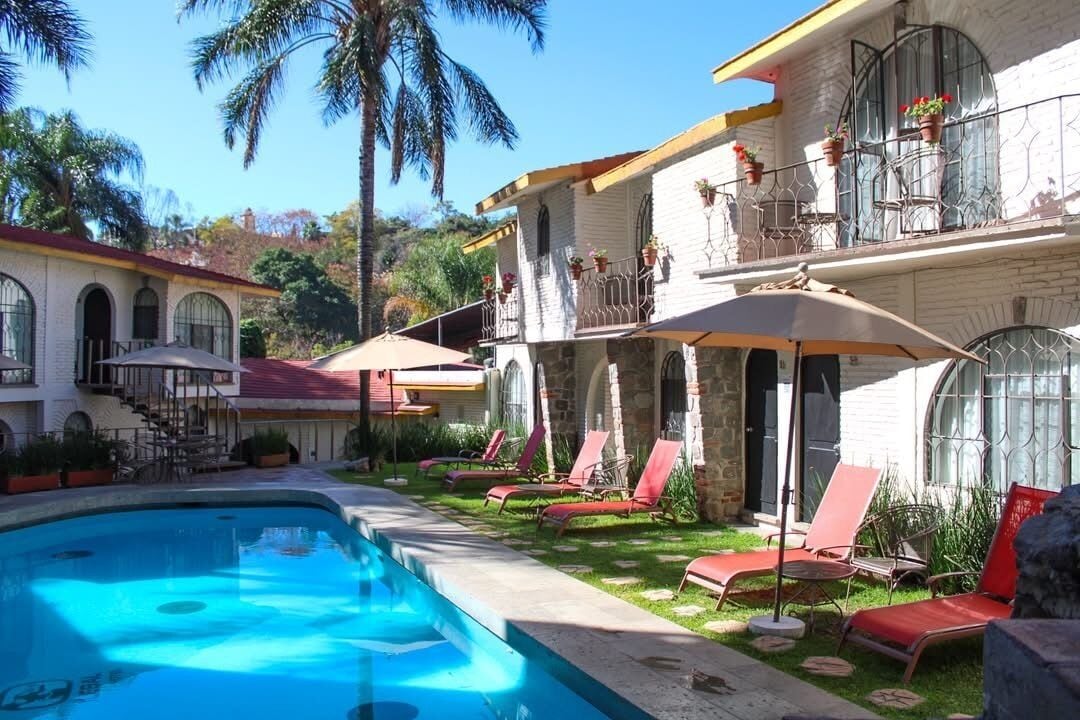 Un área de piscina con sillones de descanso y una piscina azul cristalina.
