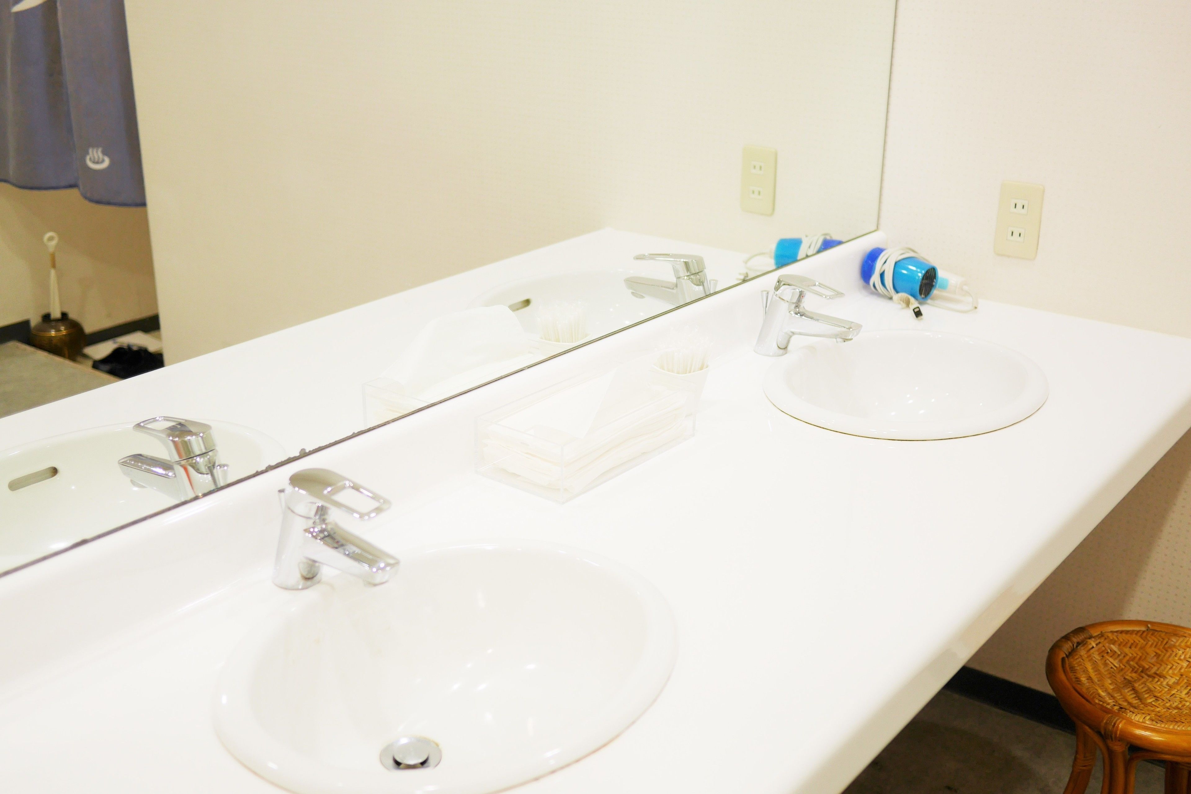 A bathroom with two sinks, a mirror, and a wooden stool.