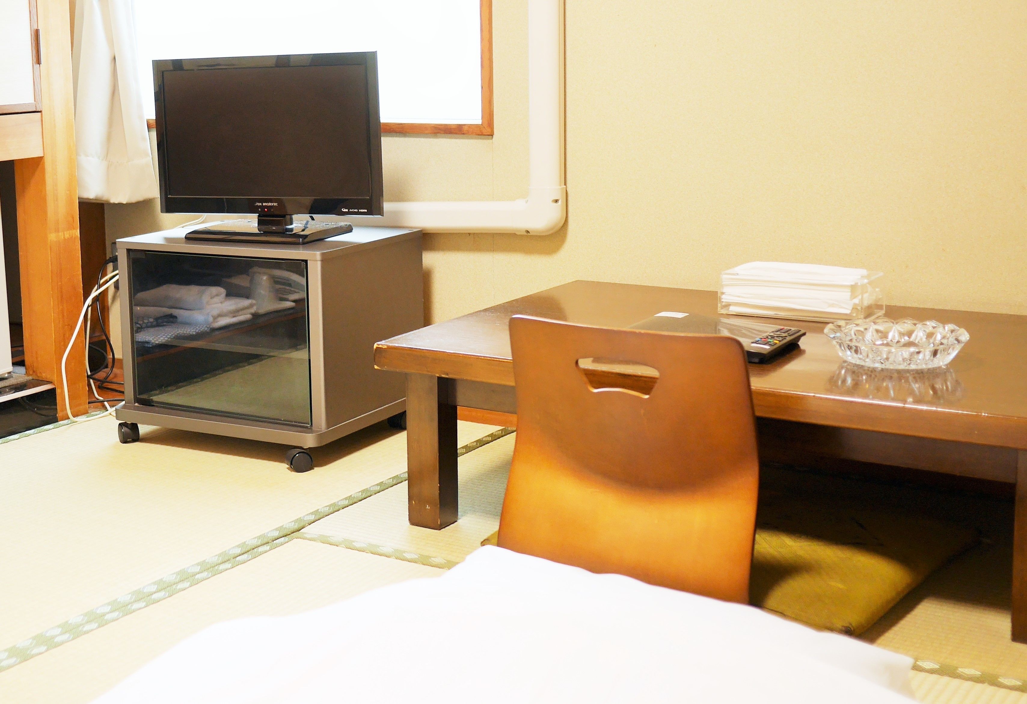 A room with a desk, a television, a small cabinet, and a chair.