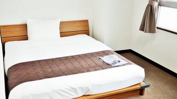 Een bed met een houten hoofdeinde, witte beddengoed en een bruine deken.